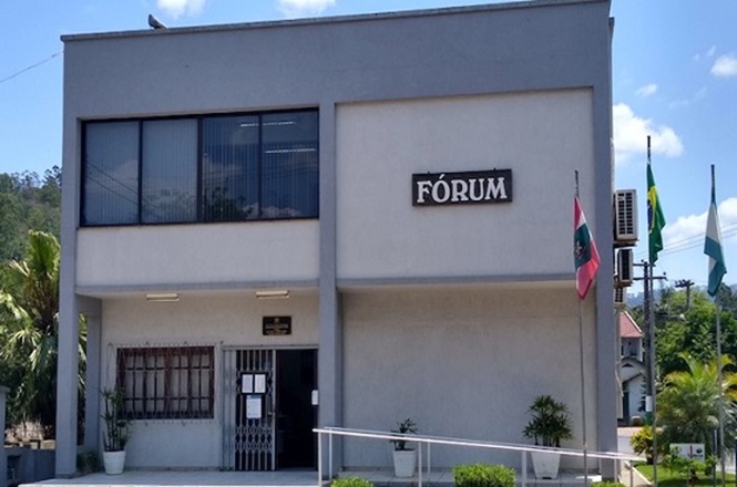 Foto horizontal: fachada do Fórum da comarca de Presidente Getúlio, com entrada principal, rampa de acessibilidade e bandeiras.