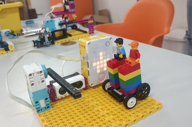 Foto horizontal: robô educacional montado com blocos coloridos sobre base, componentes eletrônicos em destaque, clima de criatividade, inovação e aprendizado tecnológico.