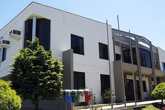 Foto horizontal: fachada do fórum de Santa Cecília, prédio institucional com área verde e coletores seletivos em destaque, clima de acesso à Justiça.