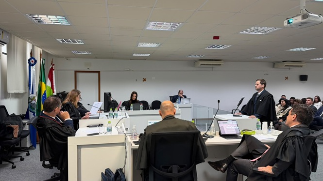 Foto horizontal: advogado faz sustentação oral diante de magistrados durante sessão de julgamento.
