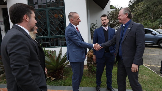 Foto horizontal: presidente do TJSC, desembargador Rubens Schulz, cumprimenta autoridade com aperto de mãos, acompanhado por outras pessoas em área externa.