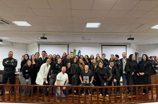 Foto horizontal: participantes e organizadores posam para registro coletivo após simulado e atividade de capacitação realizada em ambiente do Poder Judiciário.