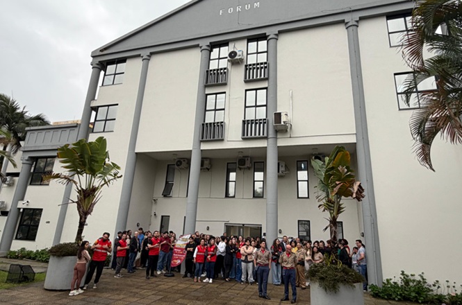 Foto horizontal: grupo de pessoas se reúne diante da fachada do Fórum de Itajaí durante simulado de emergência.