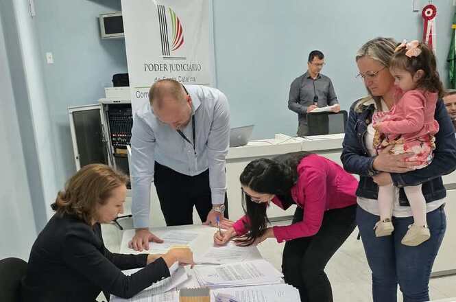 Foto horizontal: Representante de entidade assina termo de recebimento de recursos do PJSC Mais Social durante solenidade.