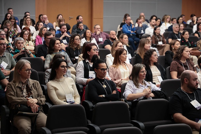 Foto horizontal: público acompanha atentamente palestra em auditório durante evento do programa SOMA.