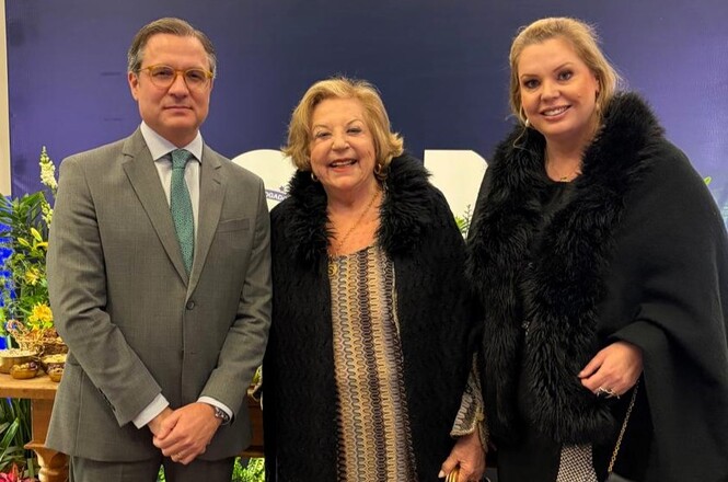 Foto horizontal: homem e duas mulheres posam juntos durante evento