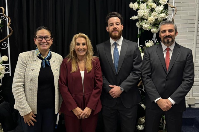 Foto horizontal: grupo posa em registro institucional, participantes alinhados em ambiente formal, clima de integração e representação institucional.