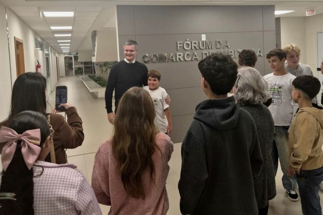Foto horizontal: estudantes registram momento com autoridade no Fórum de Imbituba, interação em destaque, clima de aproximação institucional e educação cidadã.