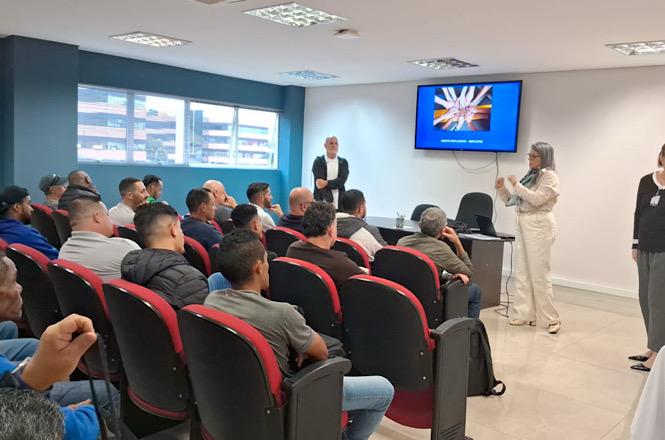 Foto horizontal: participantes acompanham palestra educativa em auditório, durante ação de conscientização e prevenção promovida pelo Poder Judiciário, com apresentação conduzida por especialista e apoio de recursos audiovisuais.