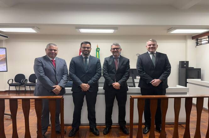 Foto horizontal: quatro autoridades posam para registro coletivo em sala de sessões.