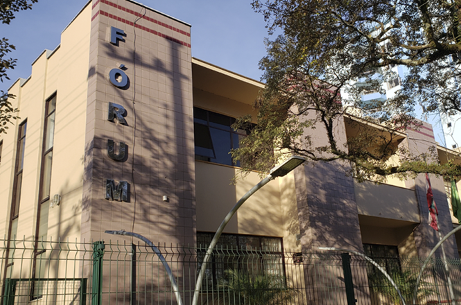 Foto horizontal: fachada do fórum de Xanxerê, prédio institucional em destaque, ambiente externo, clima de acesso à Justiça.