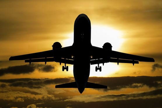 Imagem ilustrativa de avião sobrevoando céu ensolarado.