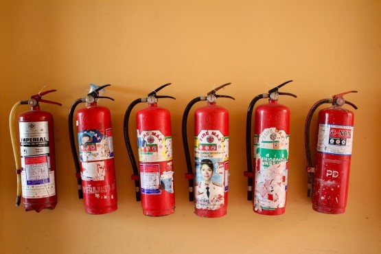 Seis extintores de incêndio na parede.