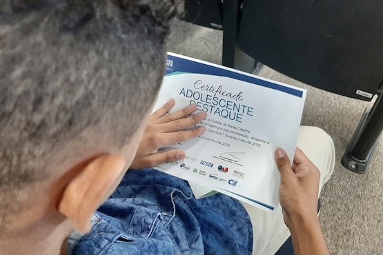 Menino segurando certificado.