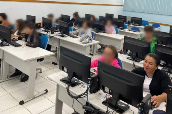 Adolescentes em frente a computadores para curso de informática.