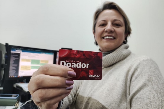 Mulher segurando sua carteirinha de doadora de sangue.