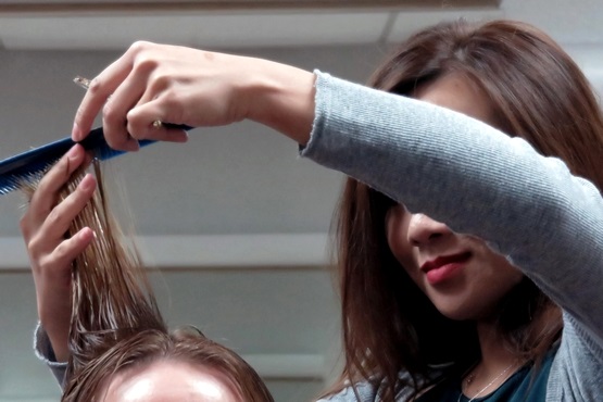 Mulher cortando o cabelo de cliente.