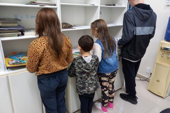 Crianças e adolescentes escolhem livros.