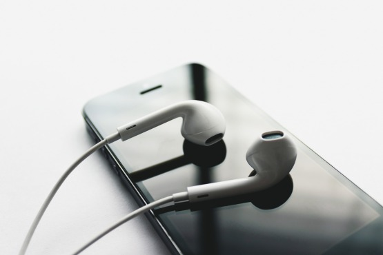 Fones de ouvido em cima de celular.