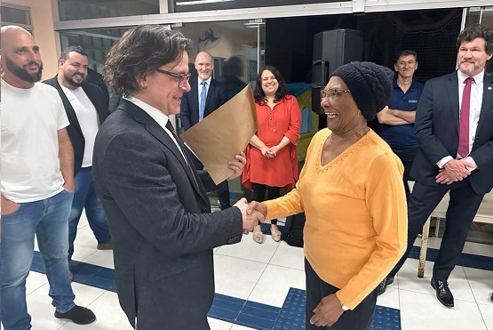 Desembargador Selso de Oliveira entrega documentação a beneficiada do programa.