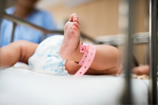 Bebê com fita identificadora em hospital.