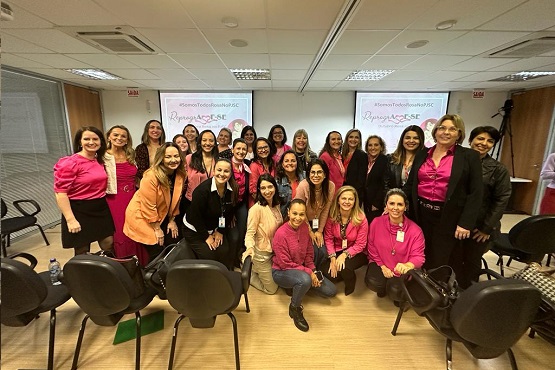 Servidores posam para foto usando roupas cor de rosa.