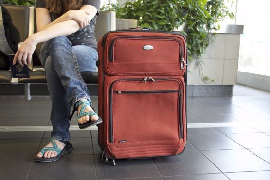 Pessoa sentada ao lado de mala de viagem.