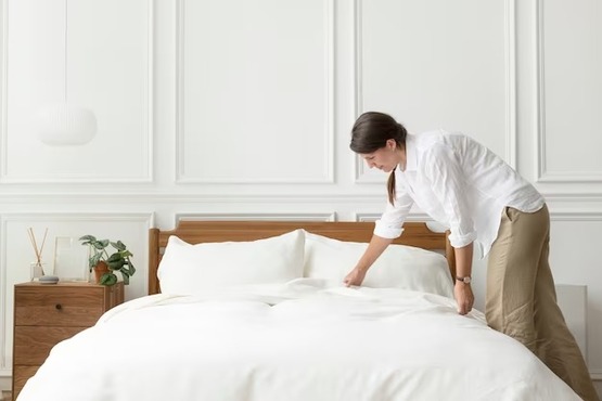 Mulher arrumando a cama.