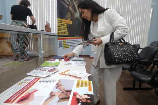 Mulher olha folders da campanha Sinal Vermelho.