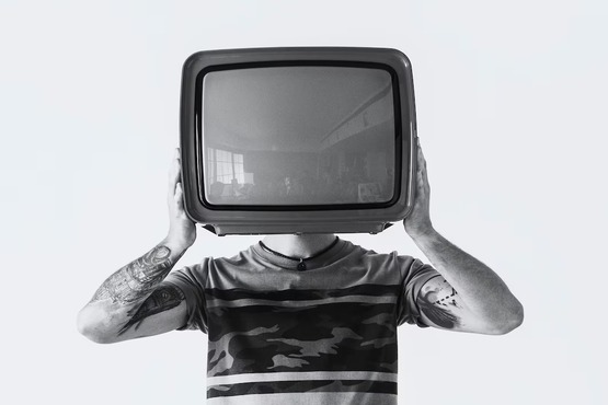 Pessoa segurando uma televisão em frente ao rosto.