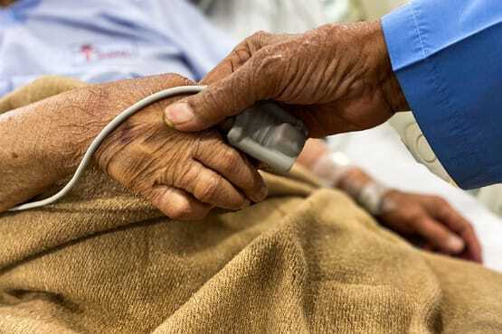 Pessoa segurando a mão de alguém hospitalizado.