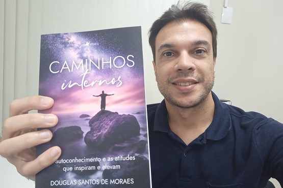 Douglas Santos de Moraes segurando seu livro.