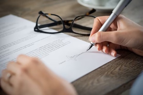 Mão de mulher assinando documento