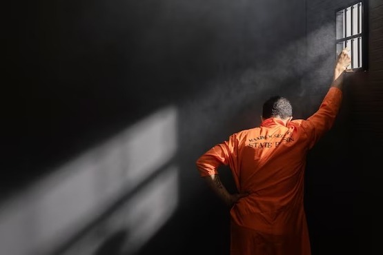 Detento com a mão nas grades da janela da cela