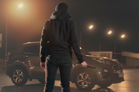 Homem de capuz prestes a arrombar carro