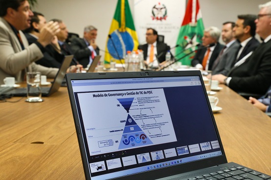 computador em foco e reunião desfocada atrás