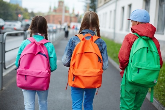 Crianças indo para a escola de mochila nas costas