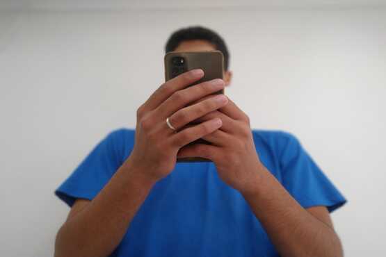 Homem com aliança no dedo mexendo no celular