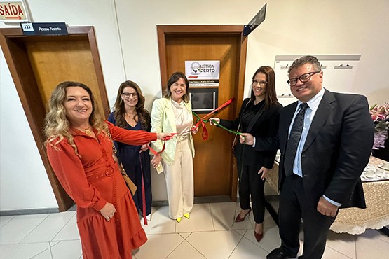 Quatro mulheres e um homem cortando fita vermelha e verde de inauguração de uma sala.