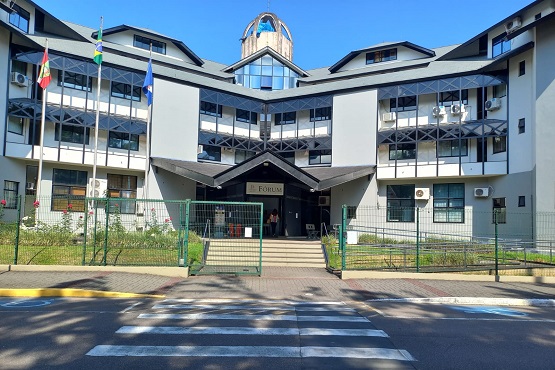Fachada do fórum de Joinville. A edificação é de três andares e possui três bandeiras hasteadas na frente.