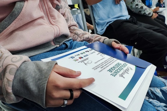 Pessoa sentada com certificado escrito “ADOLESCENTE DESTAQUE” sobre as pernas.