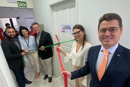 Duas mulheres e três homens seguram fita vermelha e verde para simbolizar a inauguração de uma sala do programa Ponto de Inclusão Digital.