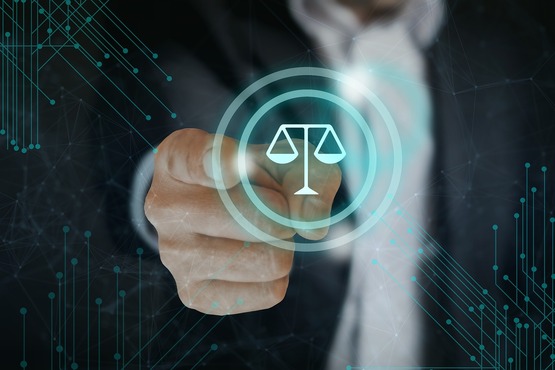 No centro da imagem, arte gráfica com um holograma de uma balança da justiça da cor azul claro dentro de duas circunferências, uma de tamanho maior e outra menor. Ao redor, há elementos gráficos simbolizando linhas tecnológicas da mesma coloração. Ao fundo, um homem tenta encostar na imagem.