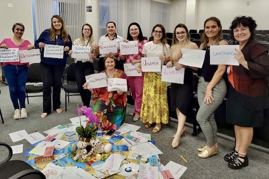 Mulheres posam para fotos segurando folhas de papel, nas quais estão escritos diversos adjetivos.