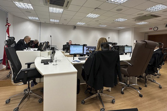 Foto tirada de uma sessão com magistrados sentados e olhando para computadores.