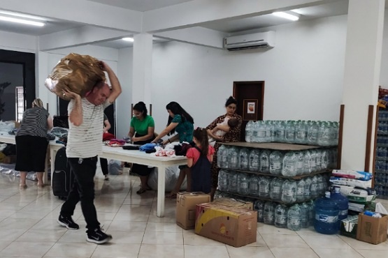 Foto de donativos sendo carregado por algumas pessoas.
