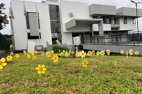 Flores amarelas confeccionadas por crianças e adolescentes no gramado em frente ao fórum de Lebon Régis.