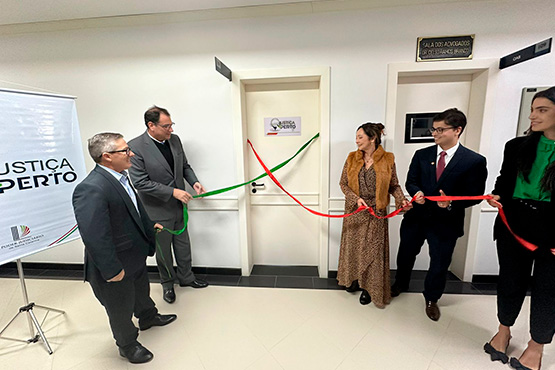 Três homens e duas mulheres, seguram uma fita verde e vermelha que envolvem a porta de uma sala.
