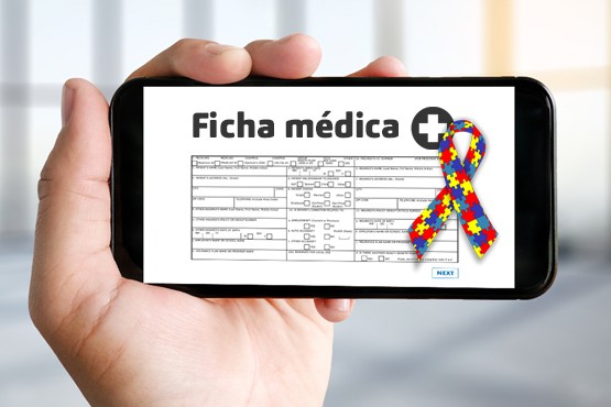 A imagem mostra uma mão segurando um celular. Na tela do celular, há uma ficha médica com o título "Ficha médica" escrito na vertical. A ficha contém várias linhas e colunas, provavelmente com informações médicas. Na parte inferior da tela, há um laço colorido com peças de quebra-cabeça, que é um símbolo associado ao autismo.