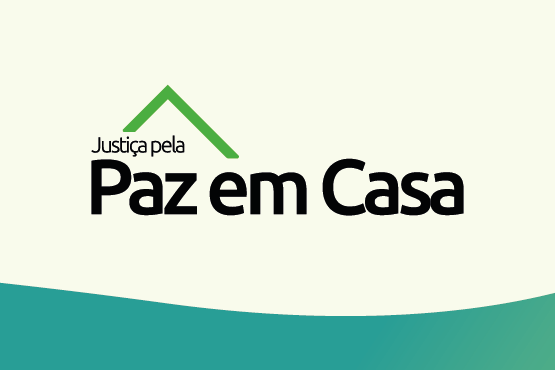 A imagem mostra um cartaz com o texto "Justiça pela Paz em Casa". O texto está disposto verticalmente e há um símbolo de seta verde apontando para cima ao lado da palavra "Justiça". À esquerda, há uma faixa verde.